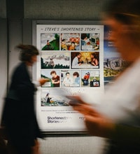 A woman walking in front of a poster