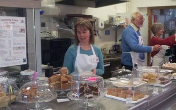 people in a kitchen preparing cakes