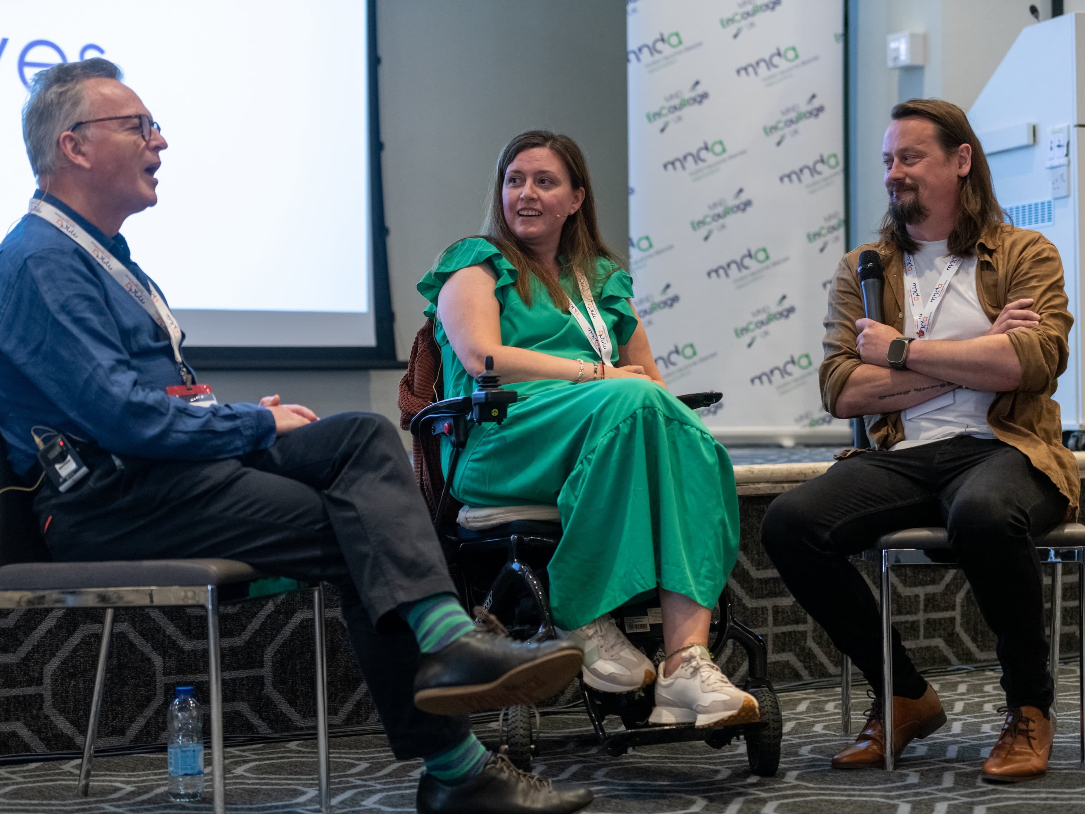 Anna and Martyn sitting in front of a stage and screen, speaking at the EnCouRage event