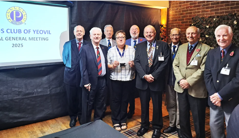 Members of the Probus Club  stood in a line with Relationship Fundraiser in the middle holding a donated cheque